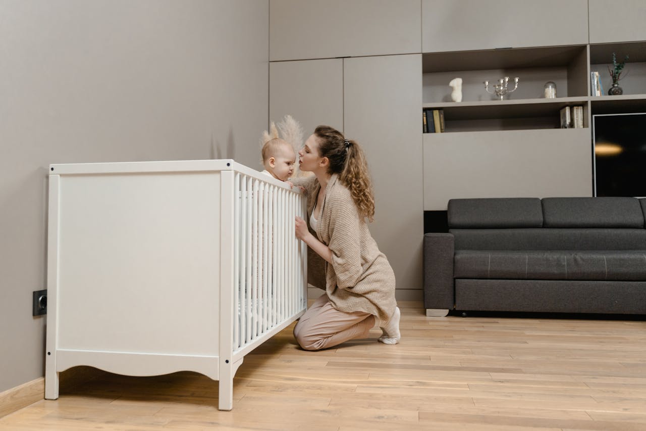 About A mother lovingly kisses her baby inside a minimalistic modern nursery with stylish decor.